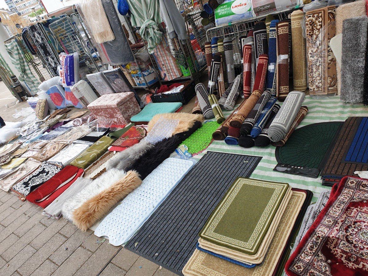 A homeware stall with rugs, bedding and household goods laid out at Chrisp Street Market